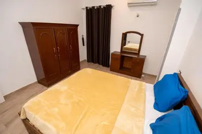 a room with a bed and a dresser and a mirror at White Flower Flats in Luxor