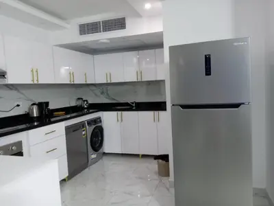 a white kitchen with a refrigerator and a dishwasher at Fanadir bay Al Ahyaa in Hurghada