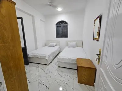 two beds in a room with white walls and marble floors at Hatschepsut hous in ‘Ezbet Abu Ḥabashi