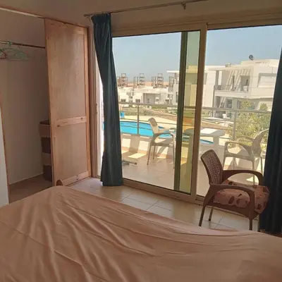 a bedroom with a bed and a balcony with a pool at George Villa in Hurghada