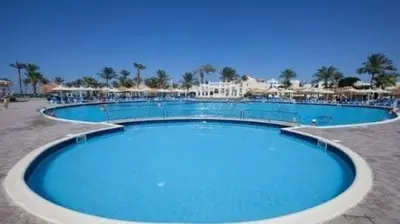 a large blue swimming pool with chairs and umbrellas at ميراج باي اكوا بارك in Hurghada