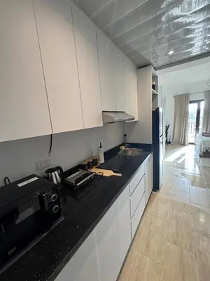 a kitchen with white cabinets and a black counter top at Aldau Heights Modern Serenity Studio in Hurghada