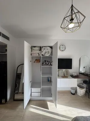 a white room with a shelf and a clock at Aldau Heights Modern Serenity Studio in Hurghada