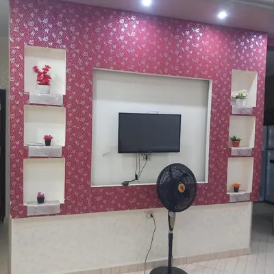 a flat screen tv on a red wall with shelves at شقه للايجار اليومي بمدينة الغردقه مميزة جدا in Hurghada