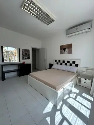 a white bedroom with a bed and a desk at Pause for a while in Hurghada