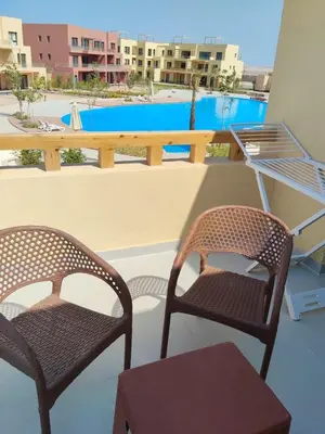 two chairs and a table on a balcony with a pool at One B2b Apartment w balcony with Jacuzzi at Makadi Heights in Hurghada