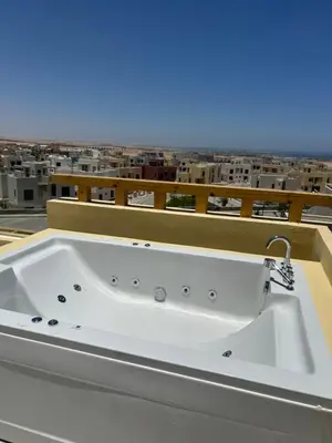 a bath tub on a balcony with a view of a city at One B2b Apartment w balcony with Jacuzzi at Makadi Heights in Hurghada