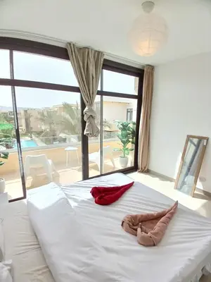 a large white bed with two pairs of shoes on it at Gcribs Onebedroom Elgouna in Hurghada