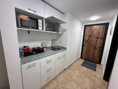 a kitchen with white cabinets and a microwave and a door at Cozy studio in Florenza Khamsim - I409 in Hurghada