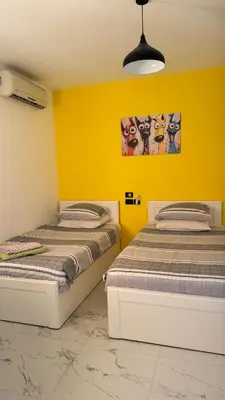 two beds in a room with yellow walls at Stylish 2BD 2Bath Regency towers in Hurghada