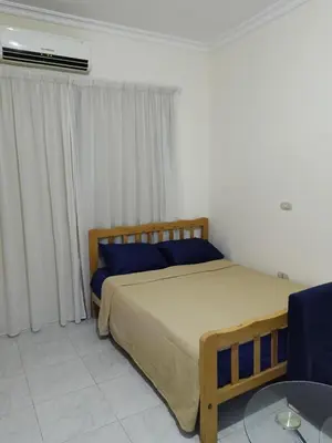 a bedroom with a bed with blue pillows and a table at Studio Lotus Compound Kawser in Hurghada