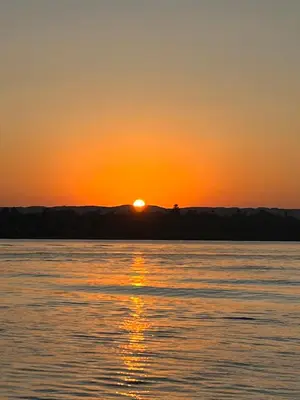 a sunset over a body of water at Aswan felucca sailing boat in Aswān