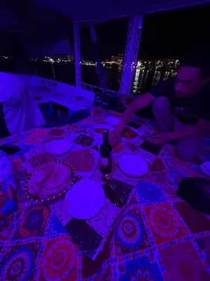 a group of people sitting at a table with food at Aswan felucca sailing boat in Aswān