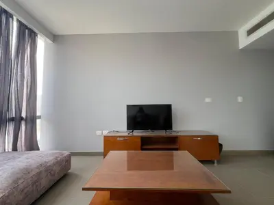 a living room with a tv and a wooden table at Bright 2Bdr with Stunning Pool Views – Sholan 1 in Hurghada
