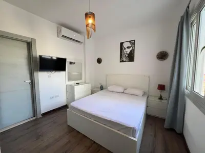 a white bedroom with a bed and a tv at Bright 2Bdr with Stunning Pool Views – Sholan 1 in Hurghada