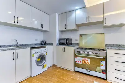 a kitchen with white cabinets and a washer and dryer at Al Saraya Sahl Hasheesh by Peaks 1 Bed Apartment with Pool View C116 in Hurghada