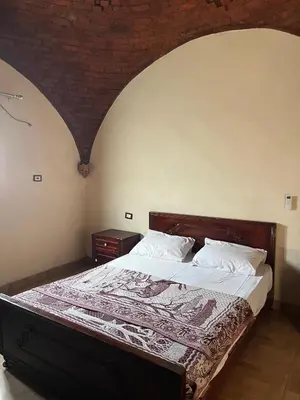 a bedroom with a large bed with a wooden headboard at Habu Palace in Luxor