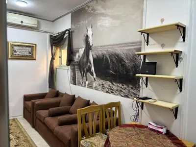 a living room with a couch and a horse picture on the wall at Apartment in Elhilal, Hurghada in Hurghada
