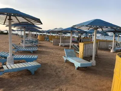 a group of blue lounge chairs and umbrellas on a beach at Apartment in Elhilal, Hurghada in Hurghada