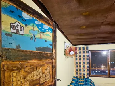 a room with a wooden door and a painting on the wall at Nubian Home by Sara in Nag` el-Ramla