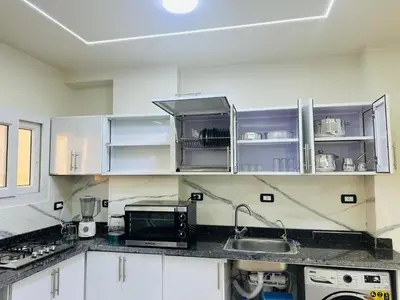 a kitchen with white cabinets and a sink and a microwave at Elite Apartment Hurghada in Hurghada