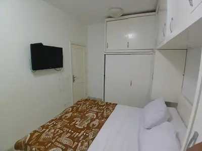 a small white room with a bed and a tv at عرابيا امام فندق بيروت بجوار سوبر ماركت الخضري in Hurghada