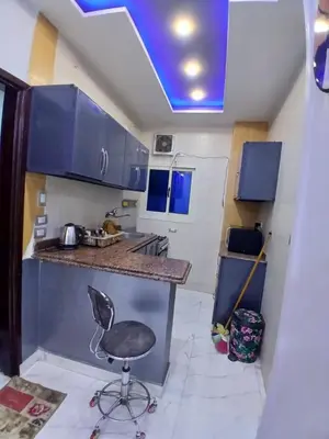 a kitchen with blue cabinets and a chair in a room at الشيراتون شارع السنترال السياحي in Hurghada