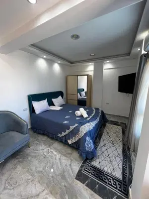 a bedroom with a blue bed and a television at Niebieski Apartament in Hurghada