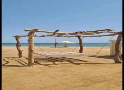 a swing on the beach with an umbrella at Niebieski Apartament in Hurghada