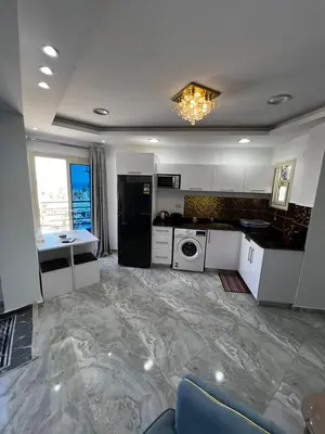 a kitchen with white cabinets and a black refrigerator at Niebieski Apartament in Hurghada