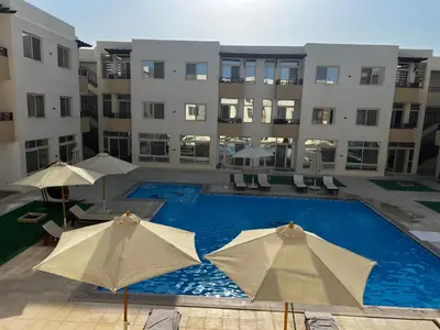 a swimming pool with umbrellas in front of a building at Royal Club Residence in Port Ghalib