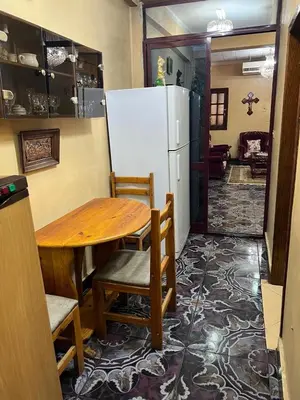 a dining room with a table and a refrigerator at Velvet Rose Apartment in Luxor