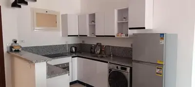 a kitchen with white cabinets and a refrigerator at 2 bedroom apartment Bay View sahl hasheesh in Hurghada