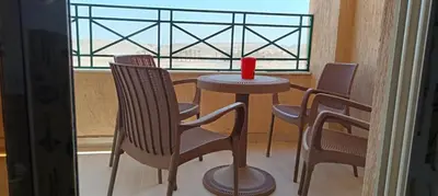 a table and chairs with a red candle on a balcony at 2 bedroom apartment Bay View sahl hasheesh in Hurghada