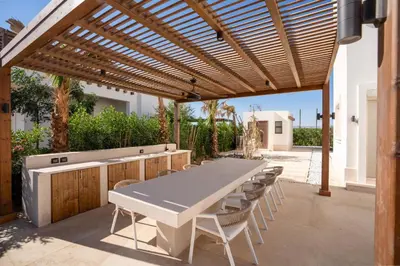 a patio with a table and chairs under a wooden pergola at Chic Cyan 4BR Villa with Private Pool in Hurghada