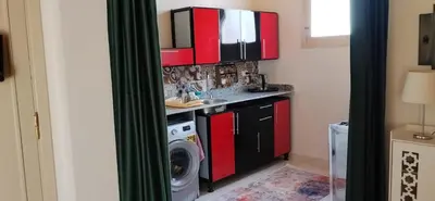 a kitchen with red cabinets and a washing machine at in luxor apartment in Luxor