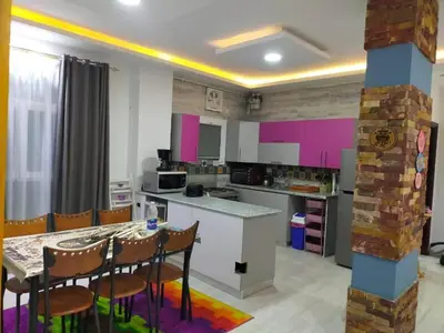 a kitchen with pink walls and a table and chairs at Apartment in villa in Magawish in Hurghada