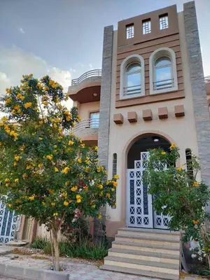 a building with a tree in front of it at Apartment in villa in Magawish in Hurghada