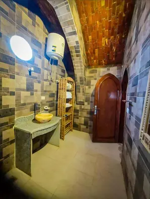 a bathroom with a sink and a wooden door at FairHaven Apartments in Luxor