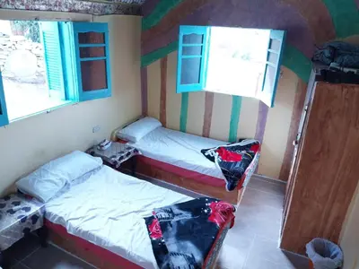a small room with two beds and a window at Shamandora Nubian Guest House in Jazīrat Fīlah