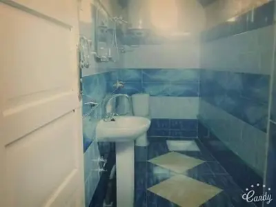 a blue and white bathroom with a sink and a shower at Shamandora Nubian Guest House in Jazīrat Fīlah
