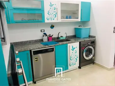 a kitchen with blue cabinets and a washer and dryer at Paradise Gates Hurghada in Hurghada