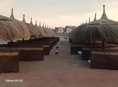 a row of straw umbrellas on a sandy beach at Fanadir Bay Premier all inclusive resort in Hurghada