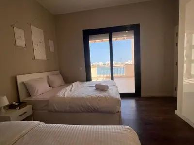 a bedroom with two beds and a large window at Cyan Luxe Retreat 3Bdr in Hurghada