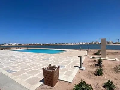 a patio with a swimming pool in front of the water at Cyan Luxe Retreat 3Bdr in Hurghada
