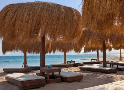 a group of straw umbrellas and benches on a beach at Soma Bay Mesca Magnificent full sea view Apt in Hurghada