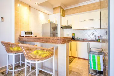 a kitchen with a counter and two chairs in it at Palm Beach Piazza Sahl Hasheesh One bedroom apartment A 401 by Peaks in Sahl Hasheesh
