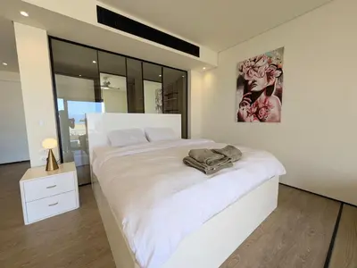 a white bedroom with a large bed and a painting on the wall at Beachfront Somabay Cabana Steps From Sea & Pool in Hurghada