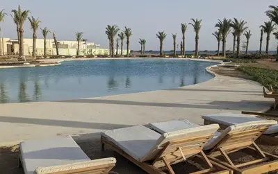 a swimming pool with lounge chairs and palm trees at Beachfront Somabay Cabana Steps From Sea & Pool in Hurghada