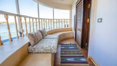 a porch with a couch on a balcony with the water at ايجبت تورز in Luxor